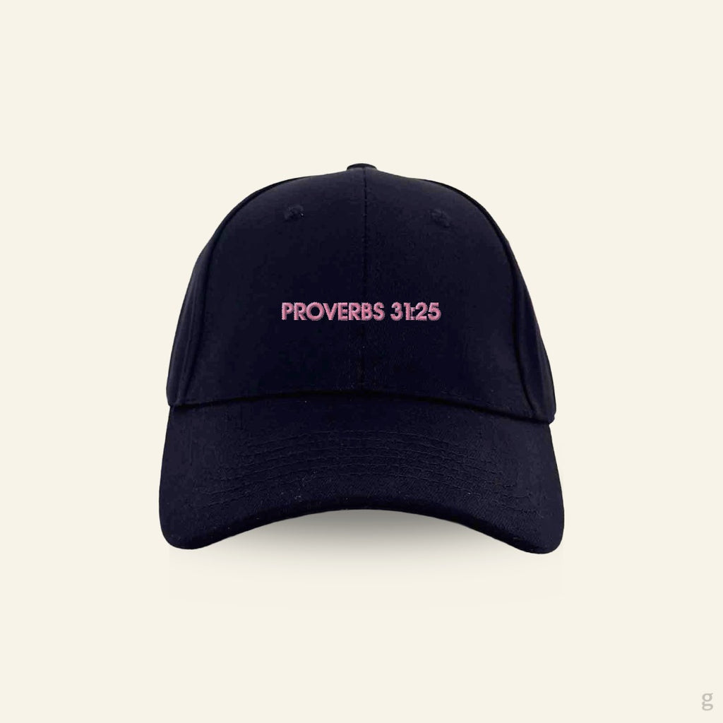 Black baseball cap with pink 'Proverbs 31:25' text on a beige background