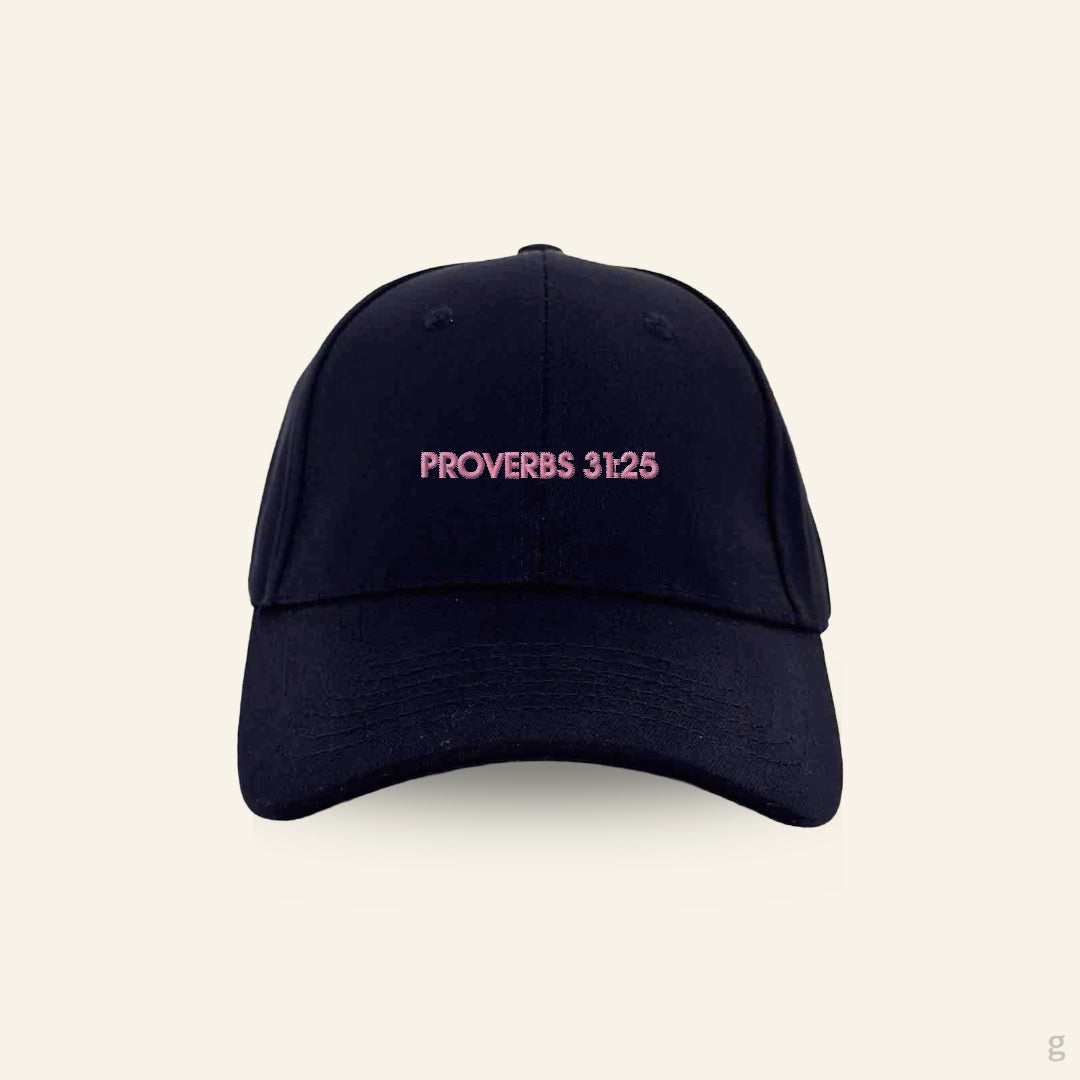Black baseball cap with pink 'Proverbs 31:25' text on a beige background