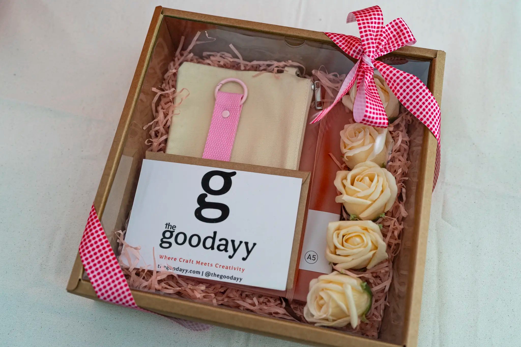 Personalized pink gift box bundle from The Fivefold Affection series with matching name printing on a dusty rose notebook, pouch, and strap tag, nestled in pink shredded paper with soap roses.