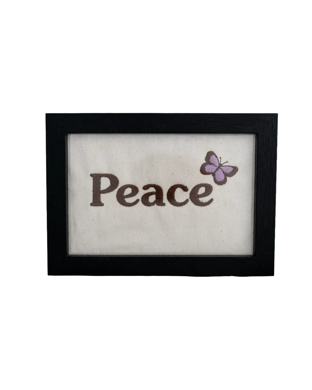 Black wood frame featuring the word "Peace" embroidered in dark thread with a purple butterfly on cream canvas.