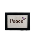 Black wood frame featuring the word "Peace" embroidered in dark thread with a purple butterfly on cream canvas.