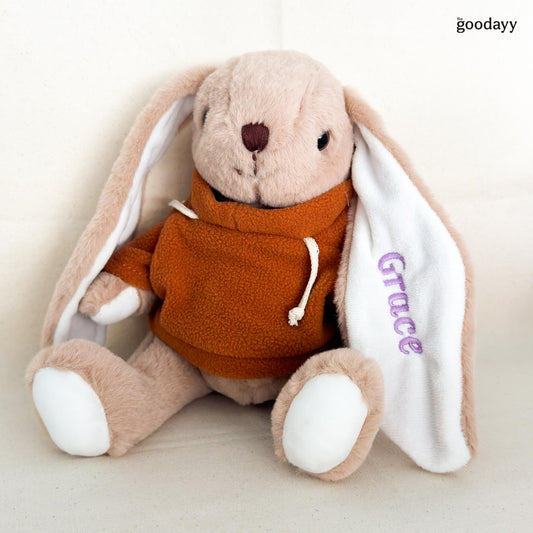 Personalized plush bunny soft toy in orange hoodie with custom name embroidery on ear in purple thread