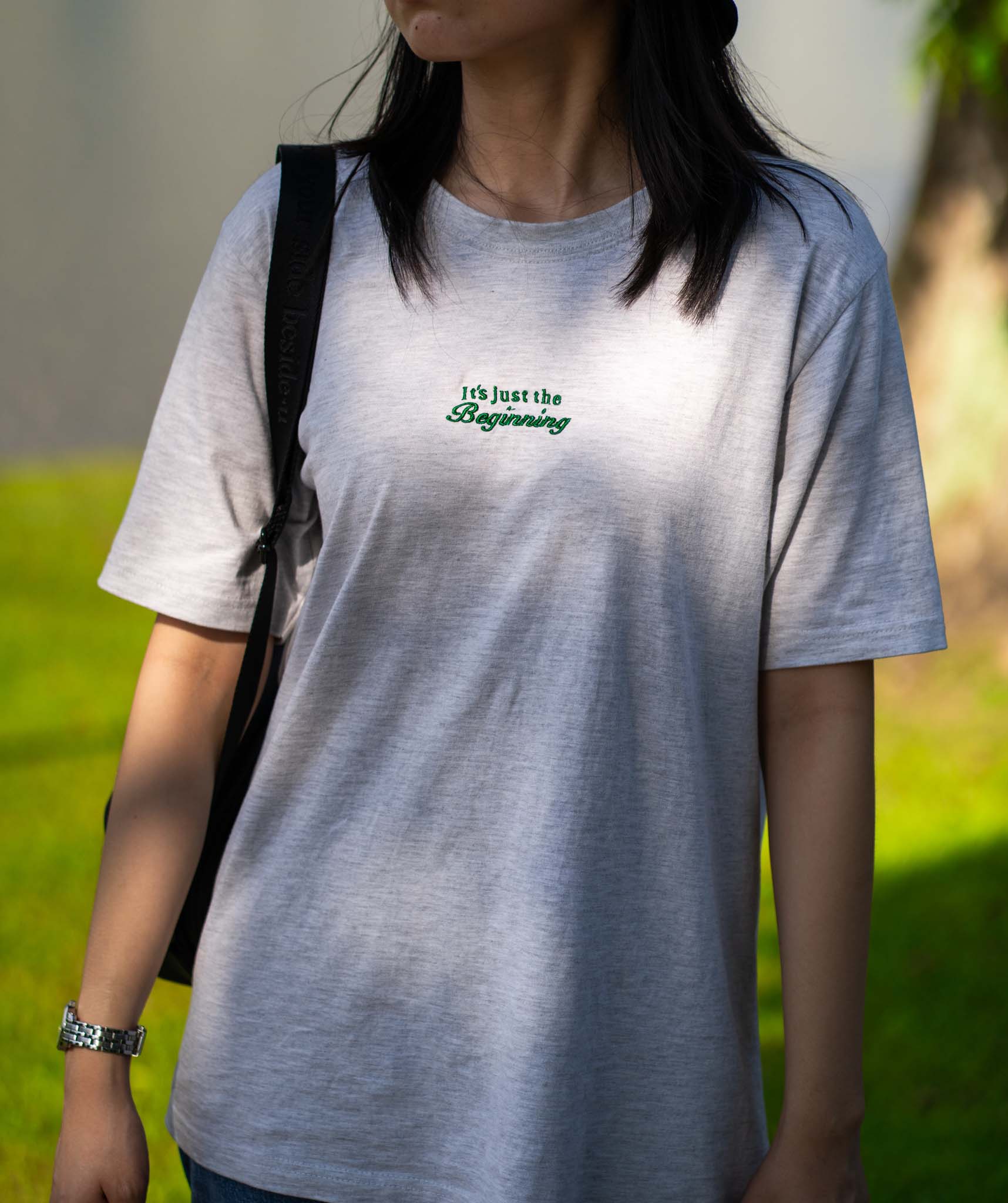 Image of model wearing  "Its just the beginning" embroidered on a 200gsm cotton tee that is available in 3 colours and available in 4 sizes, S M L XL and 2XL.