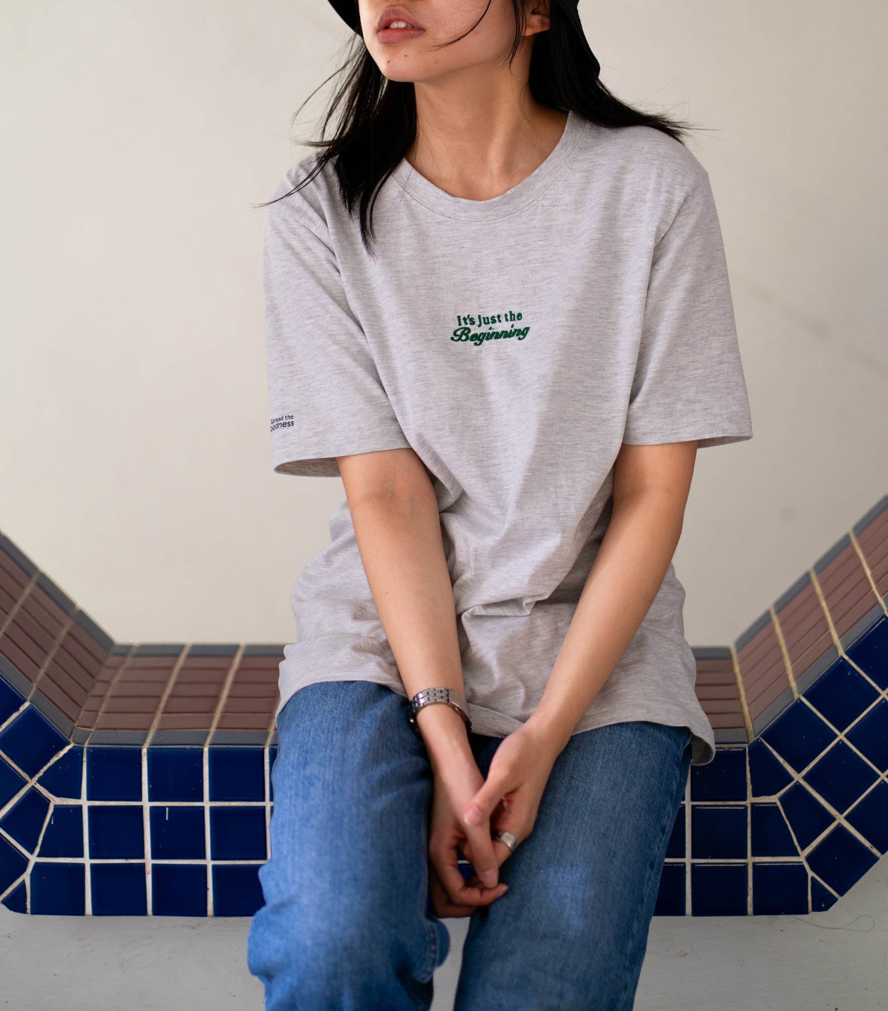 Image of model wearing  "its just the beginning" embroidered on a 200gsm cotton tee that is available in 3 colours and available in 4 sizes, S M L XL and 2XL.