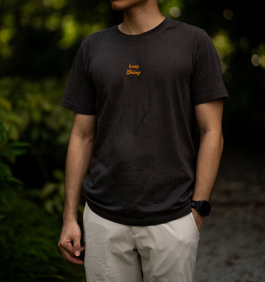 Image of model wearing  "keep going" embroidered on a 200gsm cotton tee that is available in 3 colours and available in 4 sizes, S M L XL and 2XL.