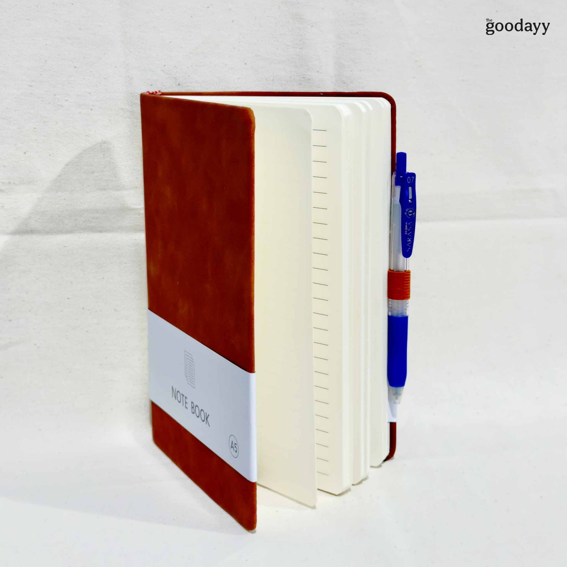 Notebook with a pen on a white background, branded 'the goodayy'.