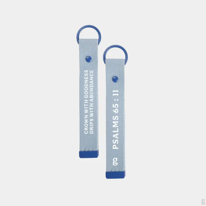 The Goodayy blue keychain strap tag with "crown with goodness, drips with abundance" and "Psalms 65 : 11" printed on the flip side
