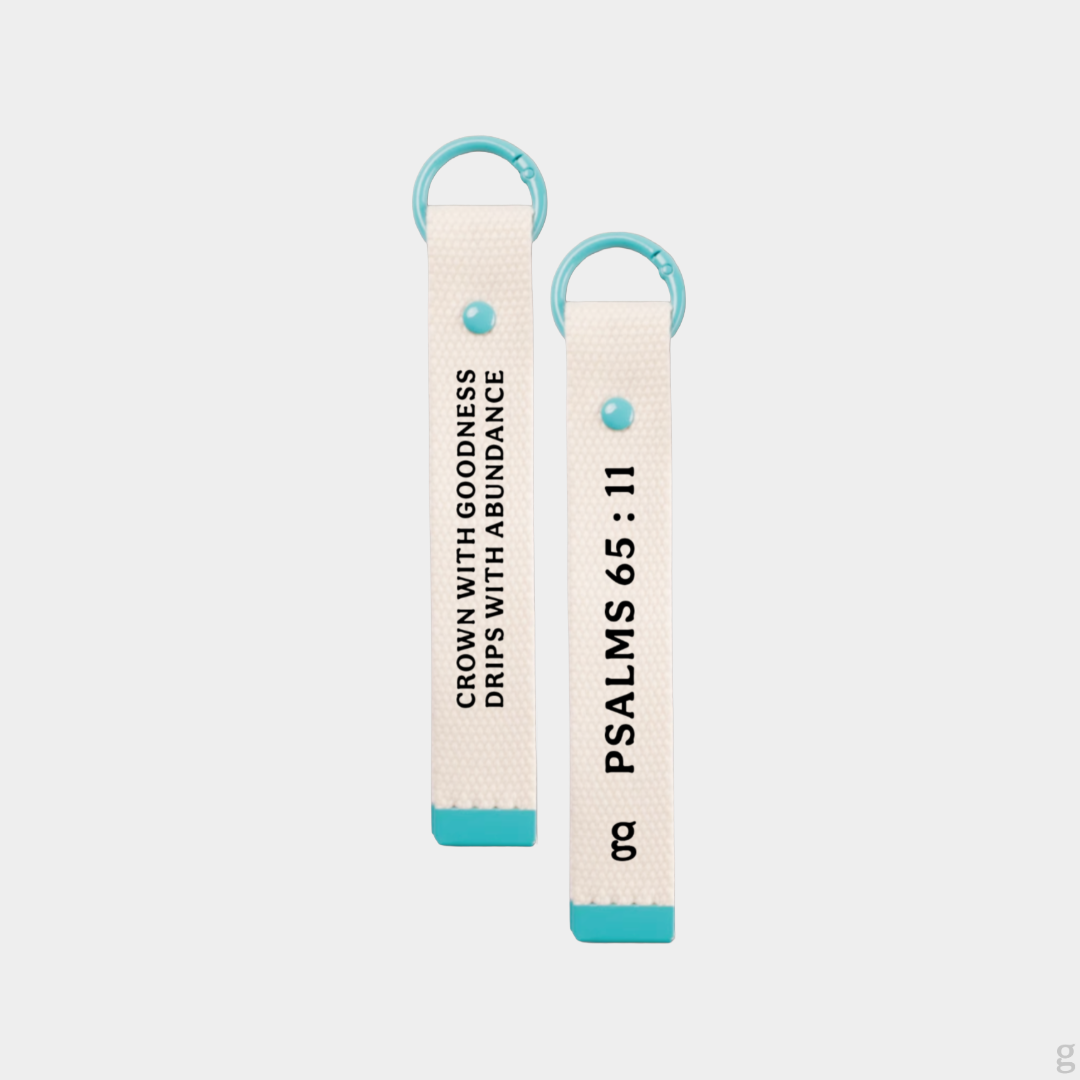 The Goodayy white keychain strap tag with "crown with goodness, drips with abundance" and "Psalms 65 : 11" printed on the flip side