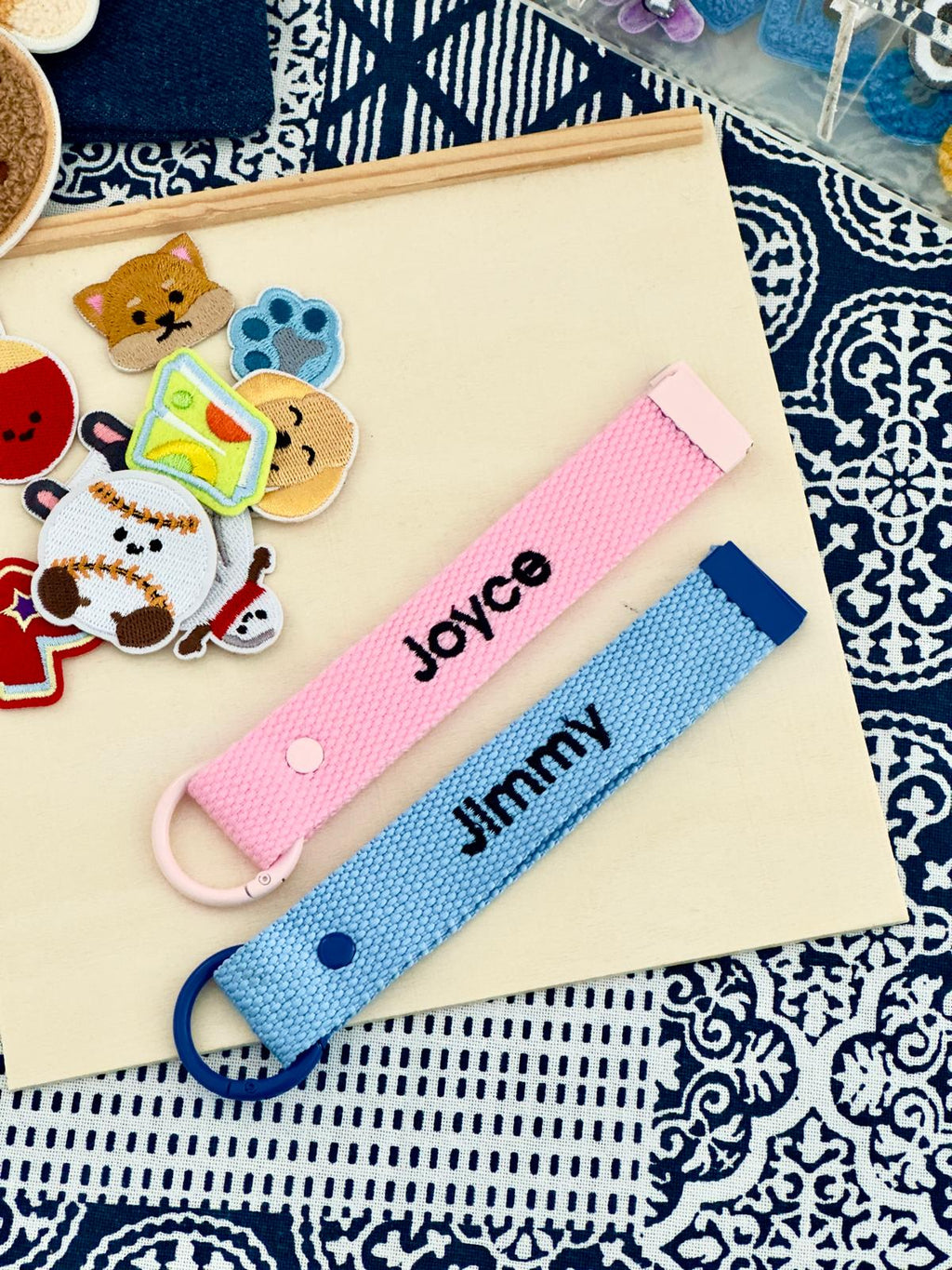 The Goodayy showcasing two personalized wristbands, one pink and one blue, with embroidered names 'Joyce' and 'Jimmy' .