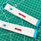 Two white personalize embroidery keychain strap with client's name "Geogre" and "Shawn" .