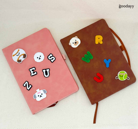 Two notebooks, one pink and one brown, with decorative stickers on a light background.